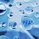Mehrere Wasserblasen mit PFAS-Label, symbolisieren Wasseranalyse und Filtertechnologie.